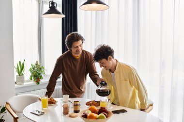 Gey çiftler keyifli bir anı paylaşırken şık dairelerinde ışık dolu kahve yapıyorlar..