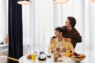 İki adam, şık dairelerinde, sevgi ve bağlarını kutlarken keyifli bir kahvaltıyı paylaşıyor..