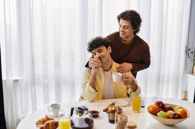 İki adam, şık evlerinde sevgi ve kahkahalarla dolu sıcak bir kahvaltı anlarını paylaşıyor..