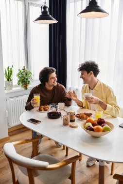 Eşcinsel çift, şık evlerinde, kahkahalar ve aşkla dolu, keyifli bir kahvaltıyı paylaşıyor..
