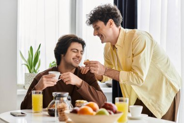 Eşcinsel çift, şık evlerinde kahveyi ve gülümsemeyi paylaşarak sıcak bir anın tadını çıkarıyor..