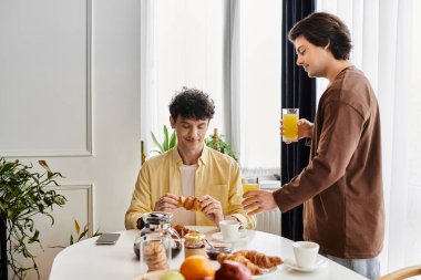 Eşcinsel çift kahvaltıdan zevk alır, gülümsemelerini paylaşır ve sıcak ortamlarında sıcak bir atmosfer oluştururlar..