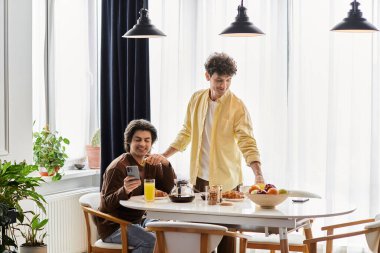 Sevgi dolu bir eşcinsel çift şık dairelerinde kahvaltıdan zevk alıyor, gülümsüyor ve rahatlıyor..