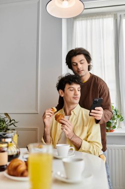 İki adam şık dairelerinde kahvaltıyı paylaşırken aynı zamanda birbirlerine eşlik ederler..