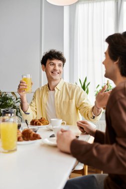 Eşcinsel çift keyifli bir kahvaltıyı paylaşıyor, gülüyorlar ve dairelerinde birlikte vakit geçiriyorlar..