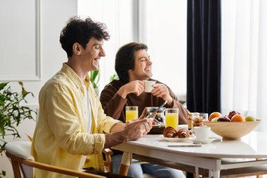 İki erkek keyifli bir kahvaltıdan zevk alır, gülümseyerek ve rahat mekanlarında birbirlerine bağlanarak..