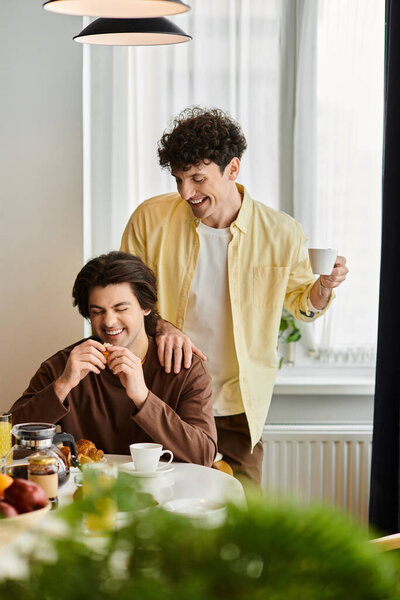 гей пара наслаждается восхитительным утром вместе, наслаждаясь завтраком в своей шикарной квартире.