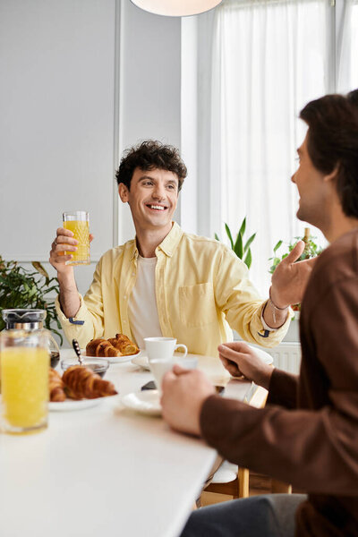 гей пара делит восхитительный завтрак, смеясь и наслаждаясь компанией друг друга в своей квартире.