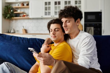 Eşcinsel çift kanepede sarılıp şık dairelerinde telefona bakıyorlar..