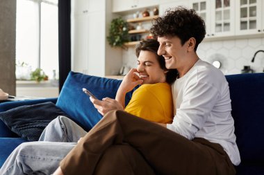 İki adam bir kanepede birbirine sarılıp kahkaha ve bağlantının tadını çıkarıyorlar..