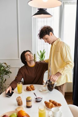 Parlak bir mutfakta, sevecen bir eşcinsel çift birlikte keyifli bir kahvaltı yapar..