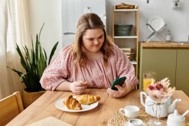Genç bir kadın lezzetli bir kahvaltıdan zevk alırken ve telefonunu kontrol ederken neşeli ve neşeli bir atmosfer..