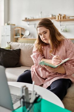 Down sendromlu genç bir kadın evdeki bir deftere yazıp rahat bir atmosferin tadını çıkarıyor..