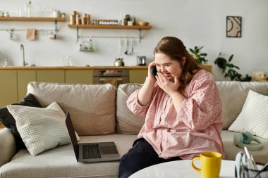 Down sendromlu genç bir kadın evdeki bir telefon görüşmesi sırasında gülümseyebilir..
