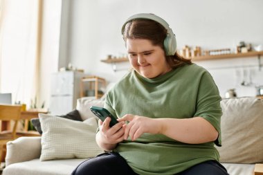 Genç bir kadın evde müzik dinlerken ve telefonunu kullanırken eğleniyor.