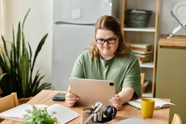 Genç ve güzel bir kadın, bitkilerle çevrili rahat bir evde tabletle meşgul oluyor..