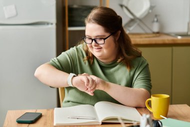 Rahat bir evde, Down sendromlu genç bir kadın saatini kontrol ederken gülümsüyor..