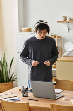 Yakışıklı genç adam sakin bir ev çalışma alanının keyfini çıkarırken dikkatle dizüstü bilgisayarında çalışıyor..