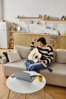 Genç Asyalı bir adam evde otururken akustik gitarda ustalaşmaya odaklanmış..