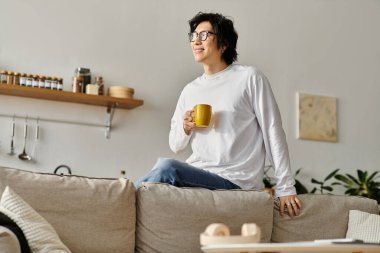 Yakışıklı genç bir adam evinde dinleniyor, sakin bir anın tadını çıkarırken kahvesini yudumluyor..