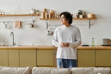 Yakışıklı bir Asyalı genç adam şık bir evde düşünceli bir şekilde duruyor, rahat ve rahat görünüyor..