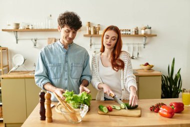 Genç bir çift evde taze bir yemek hazırlamak, gülümseme ve şefkat paylaşmak için kaliteli zaman geçirir..