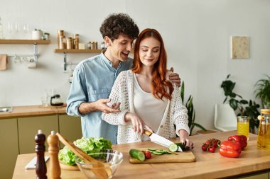 Genç çift, sevgi ve kahkahalarla çevrili evde keyifli bir yemek hazırlıyor..