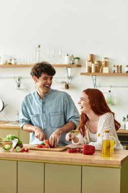Kahkaha ve aşkla meşgul olan genç bir çift, sıcak mutfaklarında birlikte yemek hazırlar..