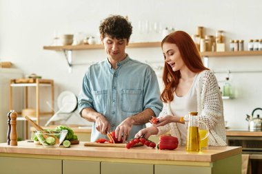 Genç bir çift, sıcak mutfaklarında birlikte yemek hazırlarken kahkaha ve sevgiyi paylaşıyor..