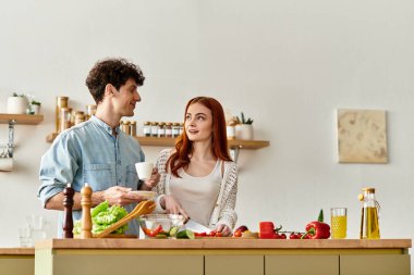 Genç bir çift, sıcak mutfaklarında birlikte yemek hazırlarken gülüşlerini ve kahkahalarını paylaşıyor..