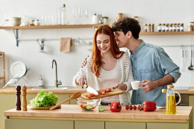 Genç bir çift, aşkla çevrili, rahat mutfaklarında neşeyle yemek pişirir..