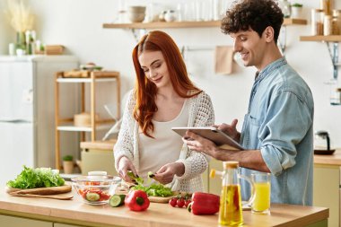 Genç bir çift, davetkar mutfaklarında birlikte sağlıklı bir yemek hazırlamak için kaliteli zaman geçirmekten zevk alır..