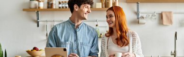 Genç çift, davetkar mutfaklarında kaliteli zaman geçirirken birbirlerine sıcak bir şekilde gülümsüyor..