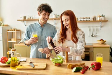 Genç bir çift, birlikte taze bir salata hazırlamak için mutfağında kaliteli zaman geçirir..