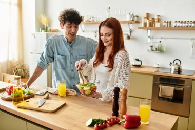 Bir çift, evlerinin mutfağında taze salata yaparak kaliteli zaman geçirmeyi seviyor..