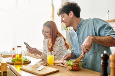 Sıcak bir mutfakta, genç bir çift keyifli anları paylaşıyor. Taze bir yemek hazırlıyor ve bağ kuruyor..