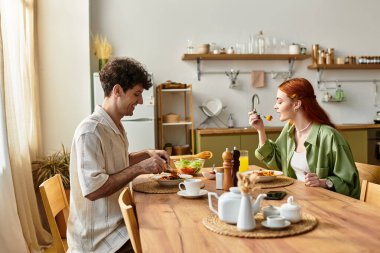 Genç çift mutfaklarında sıcak bir yemeğin tadını çıkarıyor, aşkı ve birlikteliği kutluyorlar..