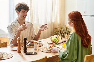 Genç bir çift evde yemek yiyor, kahkaha ve sevgi dolu..