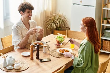 Zevkli bir yemeği paylaşan iki genç insan, sıcak ve davetkar bir mekanda birbirlerinin tadını çıkarıyorlar..