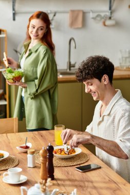Genç çift evde keyifli bir yemek yiyor, kahkaha ve aşk havayı dolduruyor..