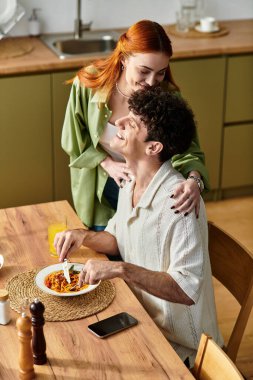 Sıcak bir mutfakta, genç bir çift ev yapımı yemeğin tadını çıkarırken keyifli bir anı paylaşıyor..