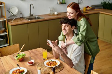 Sıcak bir mutfakta, genç bir çift gülüşlerini ve lezzetli yemeklerini paylaşıyor..