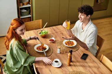 Genç bir çift gülücüklerini paylaşıyor ve evde keyifli bir yemek yiyorlar..
