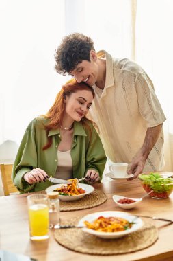 Sevgi dolu bir çift, lezzetli bir yemeğin tadını çıkarırken evlerinde iç açıcı bir anı paylaşır..
