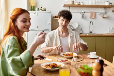 Genç bir çift evde keyifli bir akşam yemeği yer, her ısırığın tadını çıkarır ve birlikte gülerler..