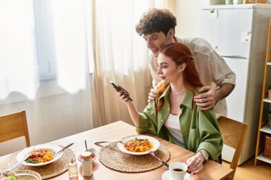 Genç bir çift evde sıcak bir yemek paylaşır, kahkaha ve şefkat dolu..