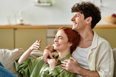 İki ortak, kanepede sıcak bir anı paylaşıyor, yaşam alanlarında aşkı kutluyorlar..