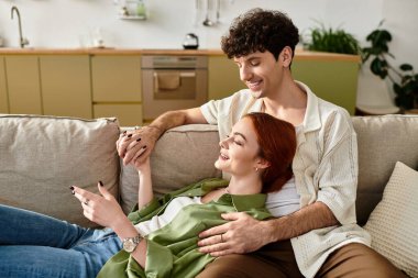 Genç bir çift, evde dinlenirken gülücüklerini ve gülüşlerini paylaşmaktan zevk alır..