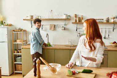 Genç çift sıcak ve davetkar evlerinde yemek hazırlarken kaliteli vakit geçirmenin keyfini çıkarıyor.