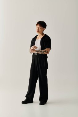 Genç ve modaya uygun Asyalı adam dengeli duruyor, modern stil ve kendine güven sergiliyor..